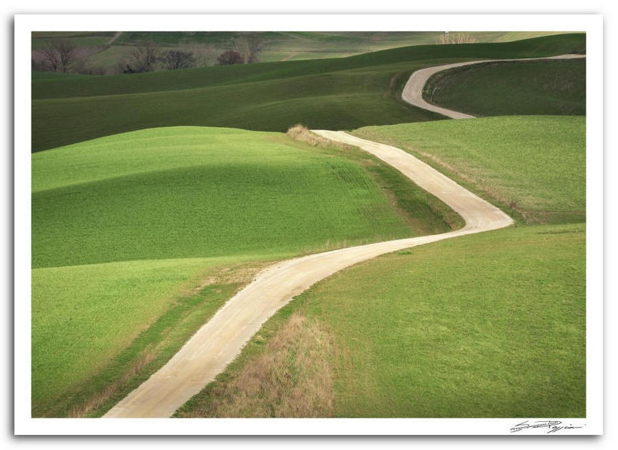 Strada bianca sinuosa tra verdi colline in campagna toscana